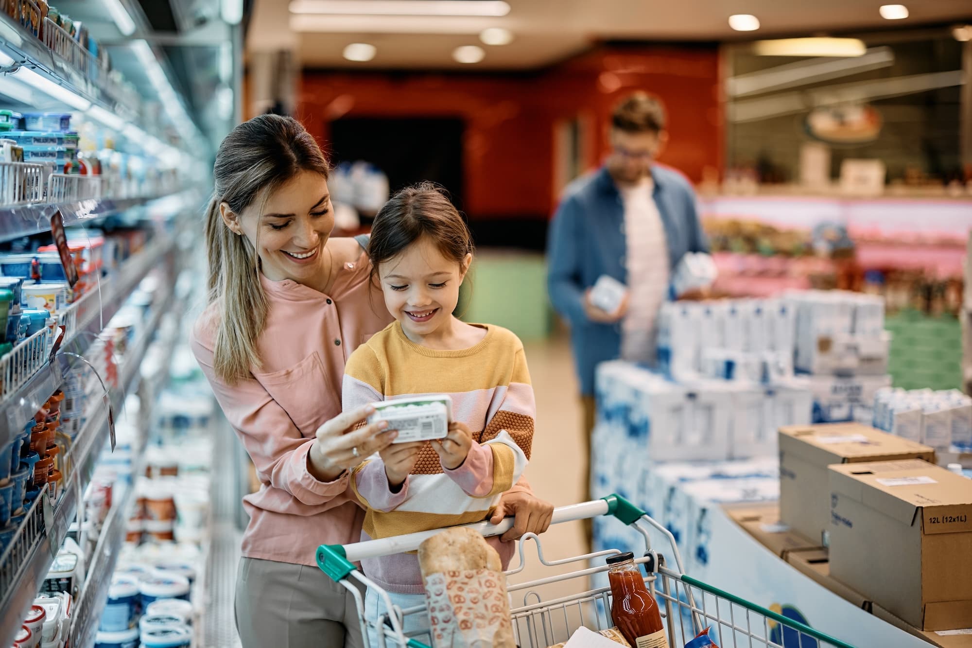 Mother and daughter reading a product label while grocery shopping